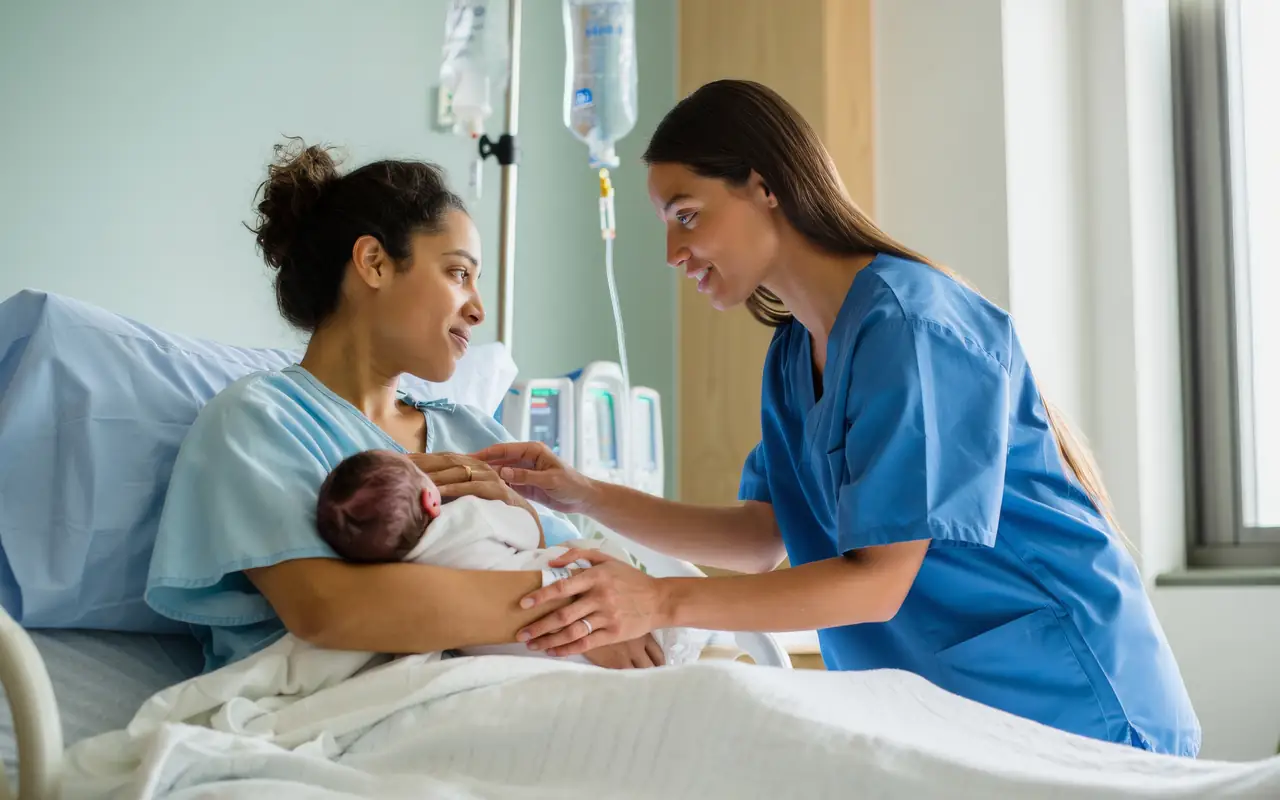 A nurse attending to a mother holding her newborn in a hospital room