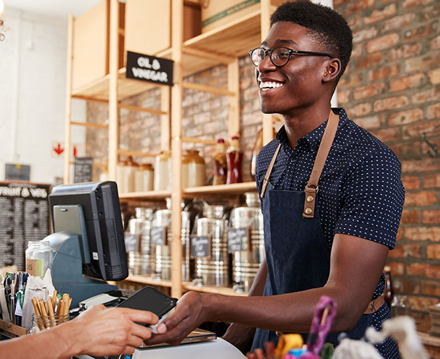 A male barista accepting card payments using GeminiPay's POS systems
