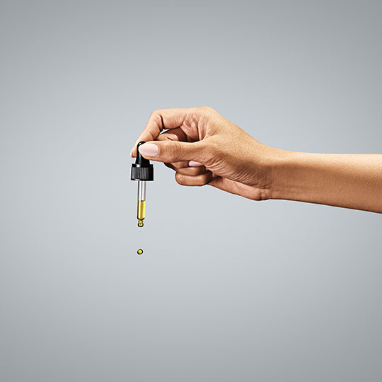 A hand holding a cbd dropper